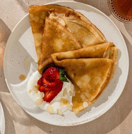 pancake with strawberries and cream on a plate